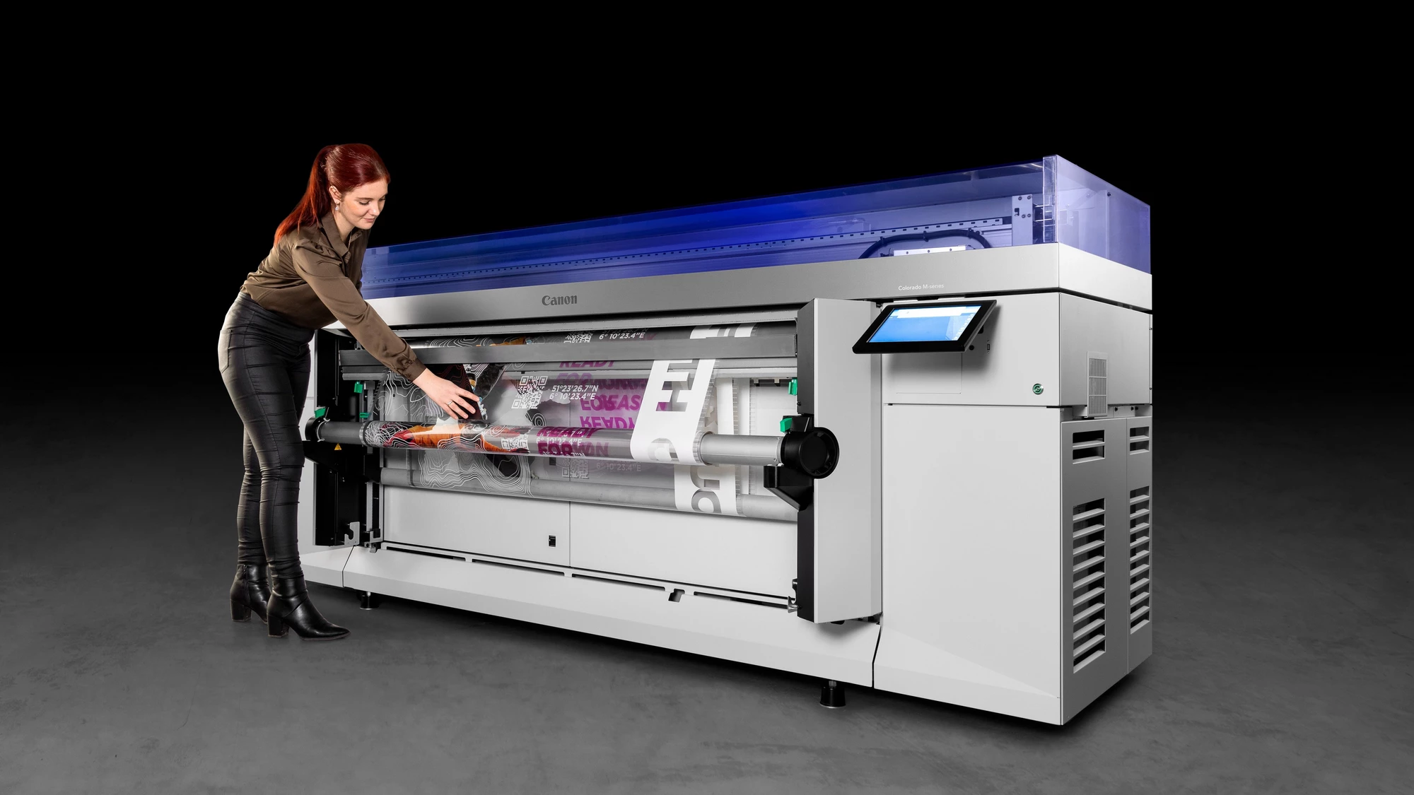 Woman loading a Canon Colorado M-Series large format printer with a print.